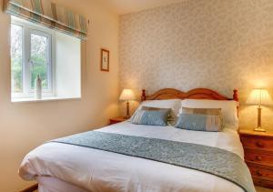 a bedroom with a bed with two lamps and a window at Owl Cottage in Llanerchymedd