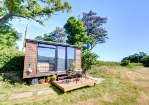 a tiny house with a deck and a table at Shepherds Hut at Ridge Hall in Staithes