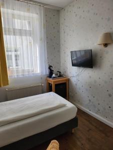 a bedroom with a bed and a television on the wall at Hotel Willert in Wismar
