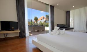 a bedroom with a bed with a tv and a large window at Villa Aquila in Seminyak