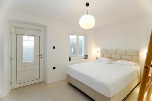 una camera da letto bianca con un letto grande e una finestra di Eternity Blue Villa a Mykonos Città Altre 29 foto