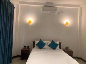 1 dormitorio con cama blanca y almohadas azules en Oqura Villa, en Ahangama