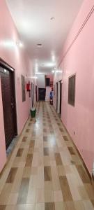 einen leeren Flur mit rosafarbenen Wänden und Holzböden in der Unterkunft Maa kaushalya Guest House in Ayodhya in Ayodhya