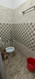 ein Badezimmer mit einem WC und einem roten Eimer in der Unterkunft Maa kaushalya Guest House in Ayodhya in Ayodhya