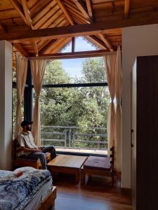 um homem sentado numa cadeira num quarto com uma grande janela em Oakakhi Stays, private room em Ranikhet