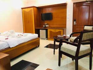 1 dormitorio con 1 cama, 1 silla y TV en Naveed Residency en Anantapur