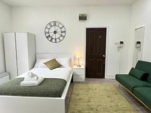 Dormitorio blanco con cama y reloj en la pared en Beautiful Studio Flat in Hackney next to Overground Station en Londres