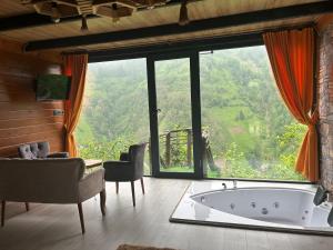 a living room with a tub in front of a large window at FİÇİTA BUNGALOv in Dikkaya
