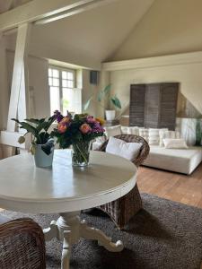 a living room with a table with a vase of flowers at The Loft in Melsele