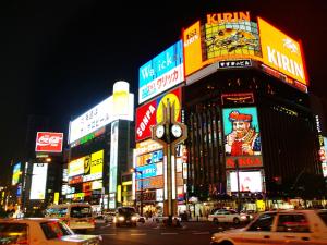 una concurrida calle de noche con coches y carteles en APA Hotel Sapporo Susukino Ekimae, en Sapporo