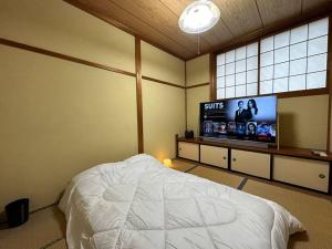 Schlafzimmer mit einem Bett und einem Flachbild-TV in der Unterkunft 百代家 飛騨高山 若達町 in Takayama