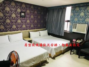 twee bedden in een kamer met schrijven op de muren bij Gui Zu Hotel in Luodong