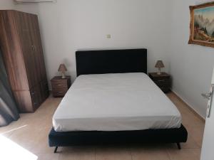 ein Bett in einem Schlafzimmer mit zwei Nachttischen und zwei Lampen in der Unterkunft B.K.group3 in Artemida