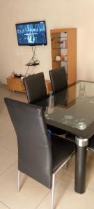 BG archange في كوتونو: طاولة طعام وكراسي مع تلفزيون في الغرفة