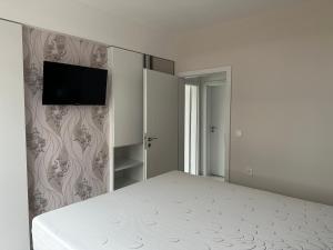 a bedroom with a bed and a tv on a wall at Сарафово Лукс Гарден Първа Линия in Burgas City