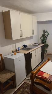 a kitchen with white cabinets and a sink and a chair at Mance Apartment in Durrës