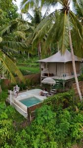 a resort with a swimming pool and a palm tree at Exotic Private Glamping in Nusa Penida