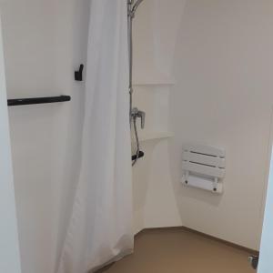 a shower in a white room with a curtain at Village Océanique in Le Bois-Plage-en-Ré