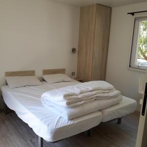 een slaapkamer met een bed met witte lakens en een raam bij Village Océanique in Le Bois-Plage-en-Ré