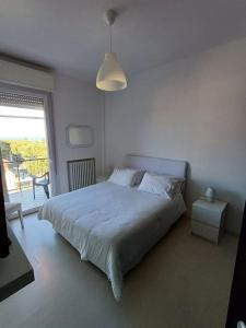 a white bedroom with a bed and a window at Appartamento vista mare Misano Adriatico in Misano Adriatico