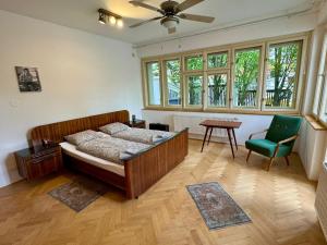 a bedroom with a bed and a chair and windows at Retro Villa Prague 700sqm Indoor-Pool, Sauna, BBQ, table soccer in Prague