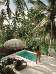 a woman in a bikini walking next to a swimming pool at Exotic Private Glamping in Nusa Penida
