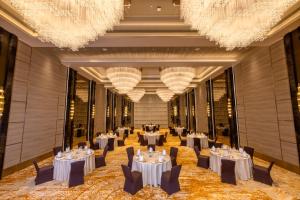 a banquet hall with tables and chairs and chandeliers at Grand Madurai by GRT Hotels in Madurai