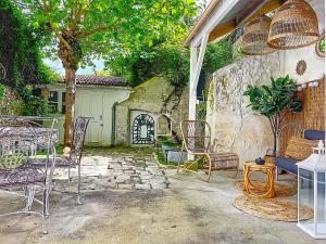 a patio with chairs and a table and a stone wall at La Romantique des Rois # Jacuzzi # Sauna in Dourdan