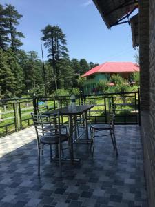 une table et des chaises assises sur une terrasse dans l'établissement Abhi Homestay- Homestay In, à Khajjiar 