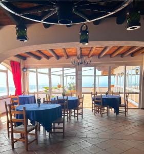 una sala da pranzo con tavoli e sedie blu e l'oceano di Hotel Punto Azzurro a Ischia