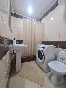 a bathroom with a toilet sink and a washing machine at Coffee Boom in Kokshetau