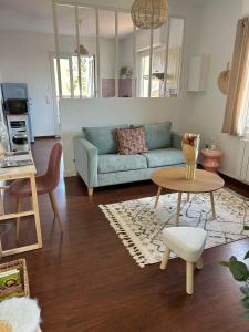 ein Wohnzimmer mit einem blauen Sofa und einem Tisch in der Unterkunft La casa magique, bulle enchantée, 100m de la plage in Andernos-les-Bains