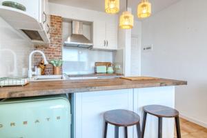 a kitchen with white cabinets and two bar stools at Apartamento de lujo con vistas al mar, a dos minutos de la playa in Calella de Palafrugell +14 photos