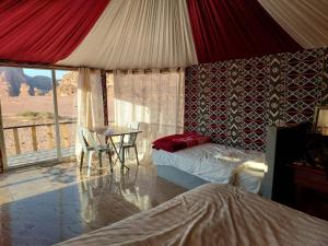 a bedroom with a bed and a table and a window at Joy to Wadi Rum in Wadi Rum
