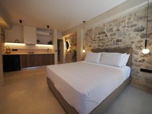 a bedroom with a large white bed and a stone wall at Sophia Town Square Areopoli in Areopolis