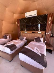 a room with three beds and a air conditioner at Wadi Rum Grand in Wadi Rum