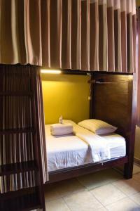 a bunk bed with white sheets and pillows on it at Desa Hostel in Munduk