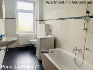 a bathroom with a tub and a toilet and a sink at Pension Kellei 71 in Dresden