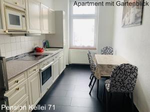 a kitchen with white cabinets and a table with chairs at Pension Kellei 71 in Dresden