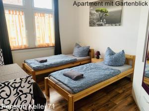 Dos camas en una habitación con almohadas azules. en Pension Kellei 71, en Dresden