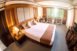 a hotel room with a large bed and a table at Lampang Wieangthong in Lampang