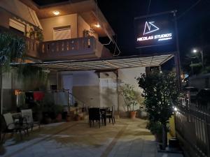 a patio with tables and chairs in a restaurant at night at Nicolas Studios & Apartments in Agia Marina Nea Kydonias