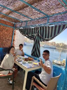 un gruppo di persone sedute a tavola che mangiano cibo di Jamaica Guest House a Aswan