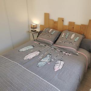 a bed with a gray blanket with feathers on it at Calme et sérenité in Le Barcarès