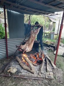 a man cooking a piece of meat over a fire at Maravillon - Chambres d'hôtes in Villon