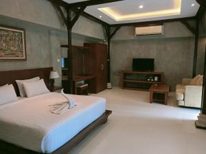 a bedroom with a bed and a tv and a couch at Uma Mani Villa Bali in Jimbaran