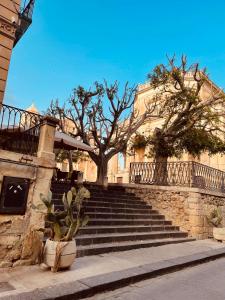 a group of stairs with a tree and a building at Il gufo barocco in Noto