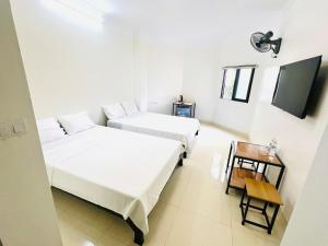 two beds in a room with a tv and a table at Spacer hotel in Ha Long