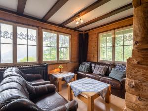 a living room with leather furniture and windows at Quietly situated group house in the southern Black Forest with a gorgeous view in Todtmoos