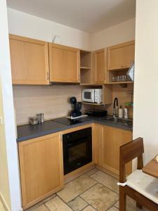 eine kleine Küche mit Holzschränken und einer Mikrowelle in der Unterkunft MARTINA Apartment KALIAKRIA RESORT in Kawarna